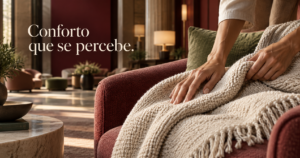 Hóspede toca a textura de uma manta dobrada sobre uma poltrona em espaço de hotel contemporâneo, em cena ilustrativa.